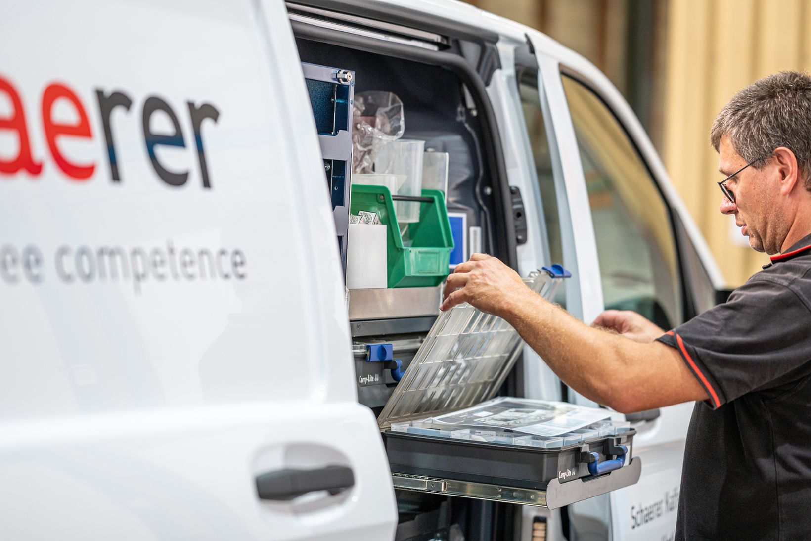 A technician organizes tools in a Schaerer service van with branded logo visible.