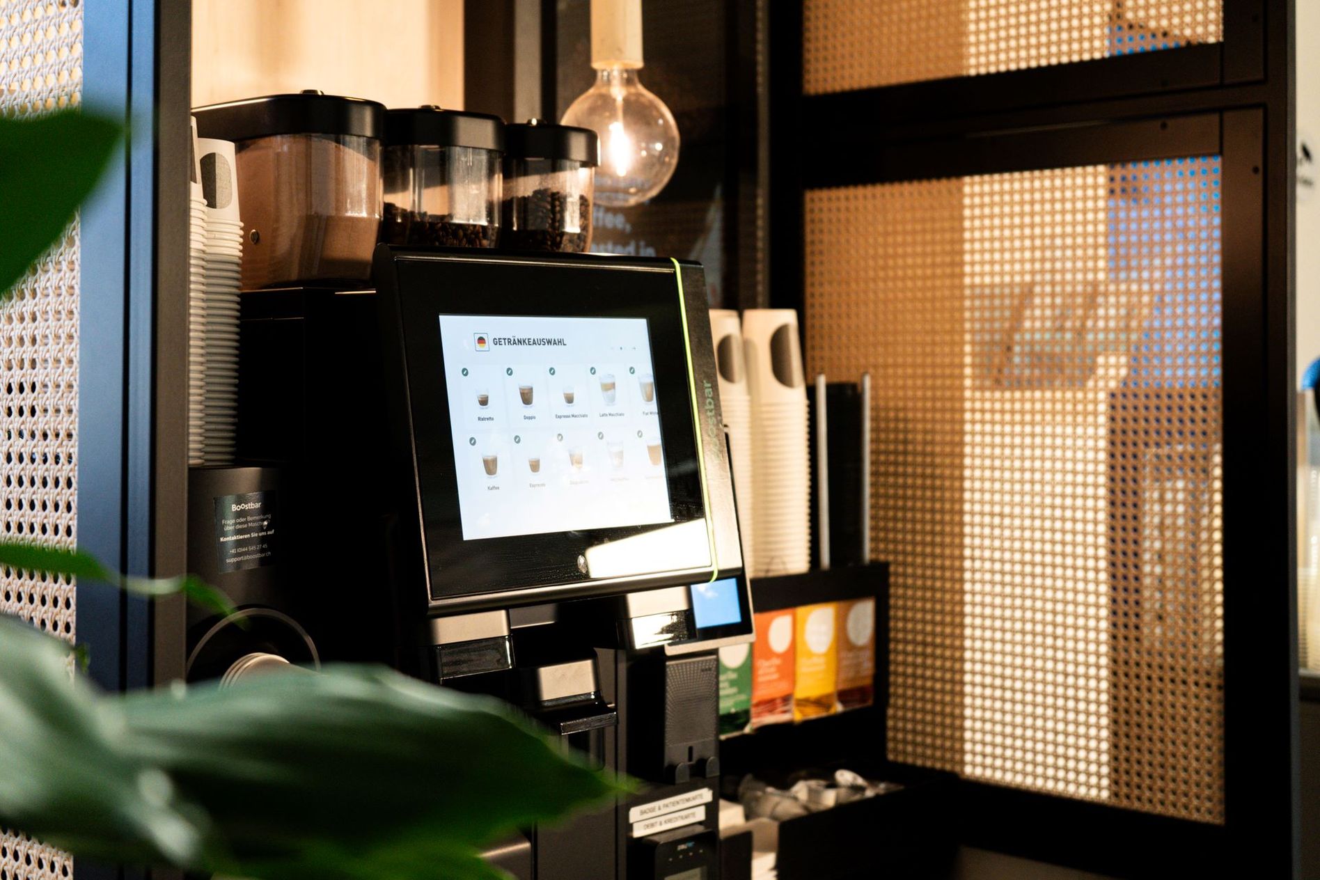 Coffee machine with digital display and various options, surrounded by cups and supplies, in a modern setting.