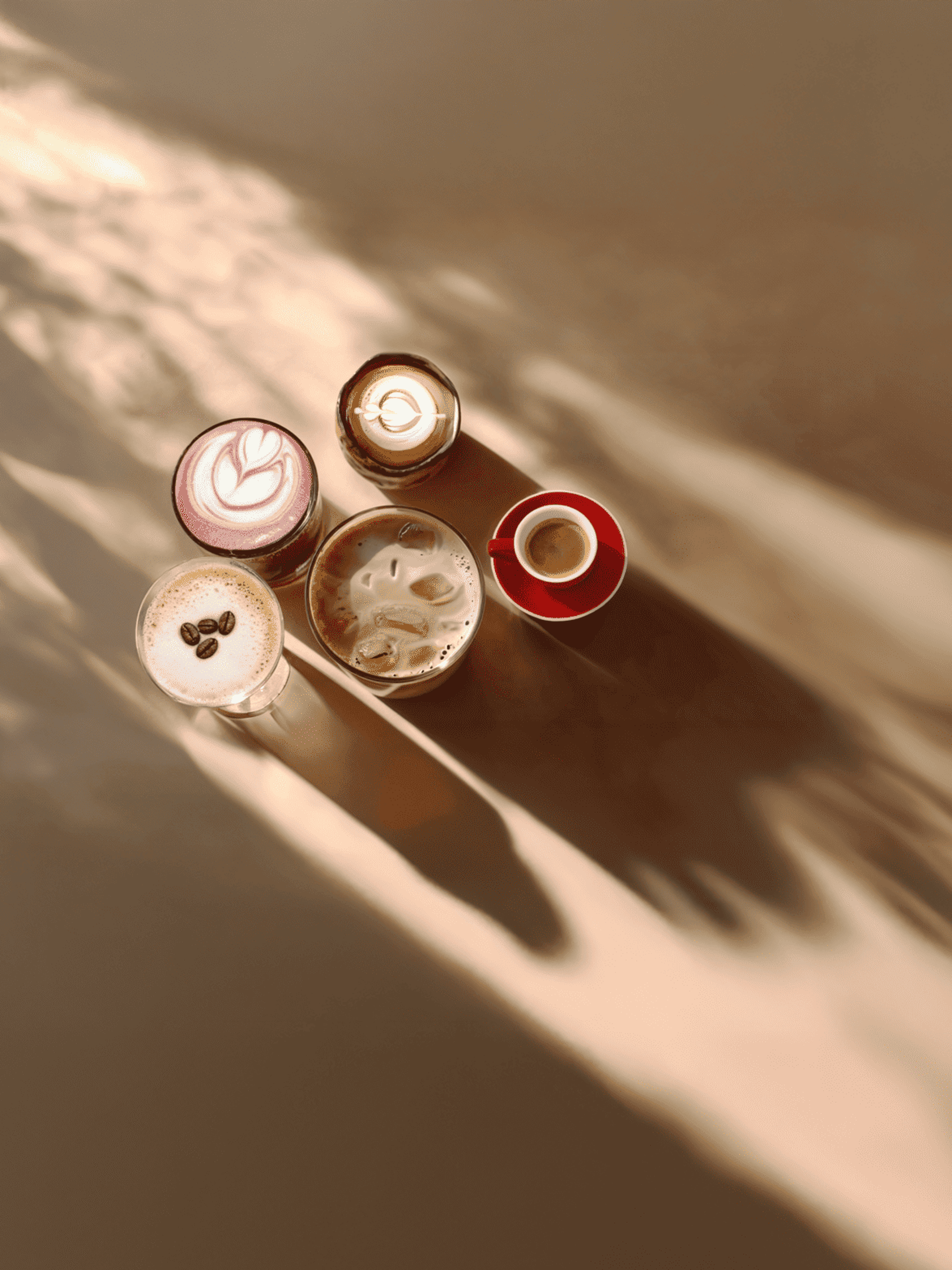 Aerial view of five artistic coffee cups with different beverages and shadow patterns on a textured brown surface.