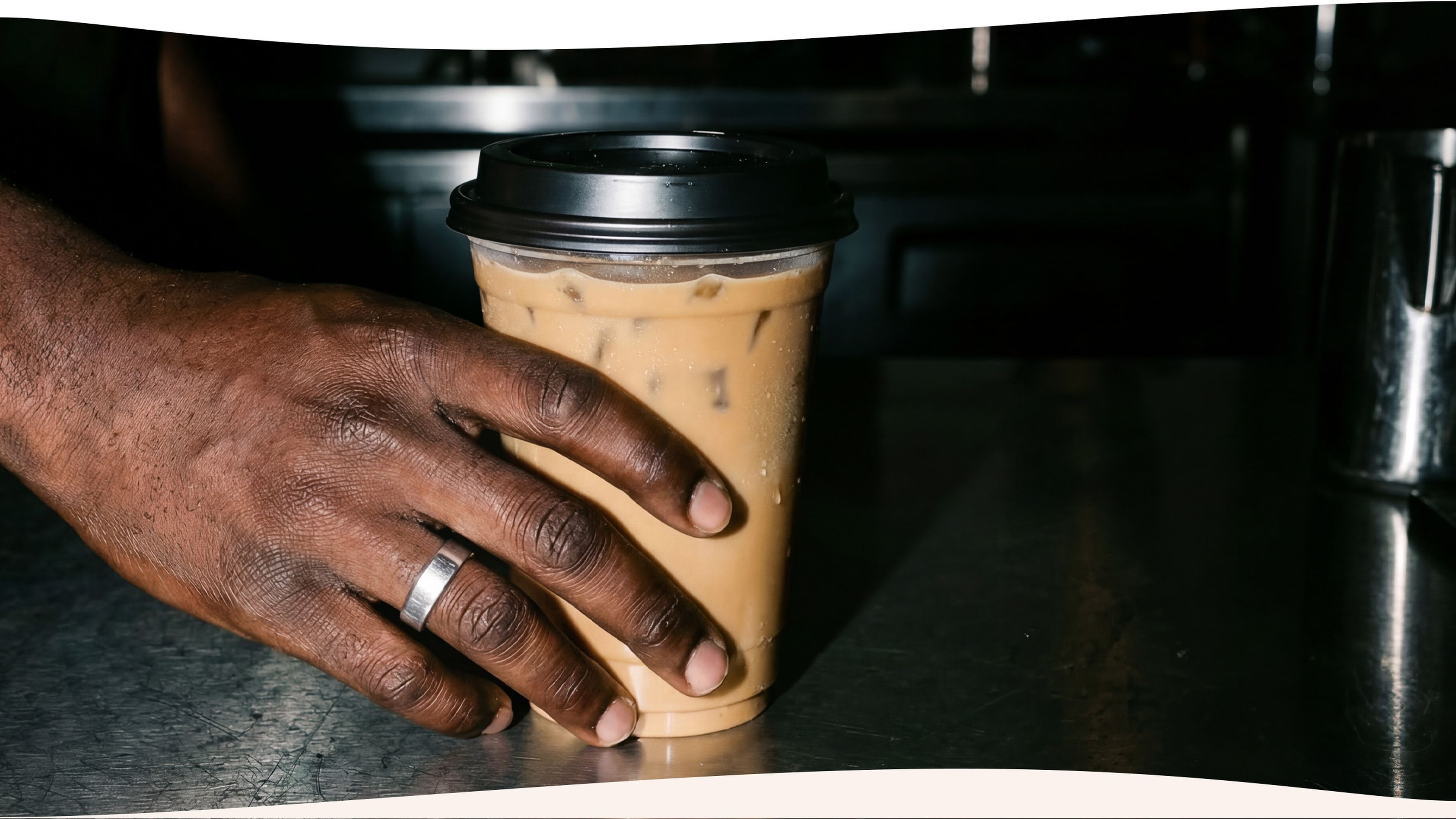 Hand with iced coffee in a to-go cup with lid